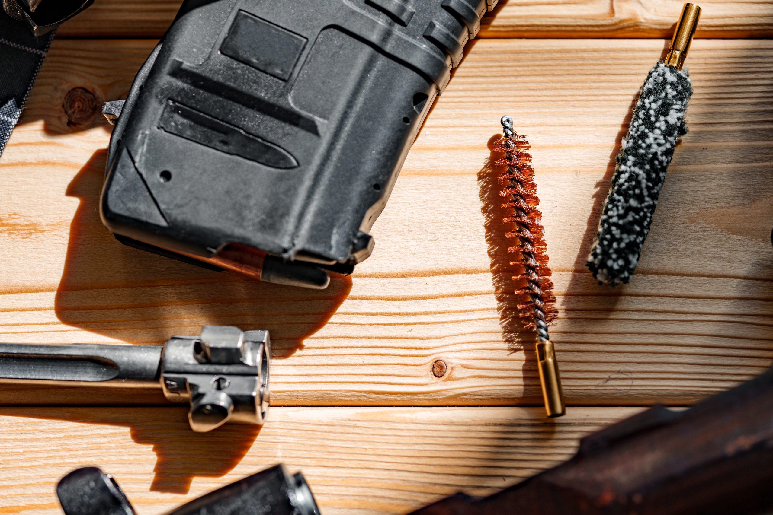 Black disassembled ar15 and cleaning tools on wooden table.